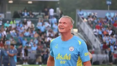Erling Haaland sorrindo com uma camiseta de treino do Man City