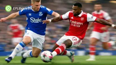 An Arsenal player turns away with the ball while holding off an Everton player