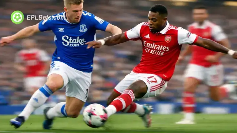 Um jogador do Arsenal se afasta com a bola, enquanto se defende de um jogador do Everton