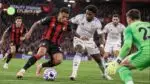 A Bournemouth attacker drives towards goal under pressure from an Aston Villa defender as the goalkeeper rushes out during a Carabao Cup clash at the Vitality Stadium.