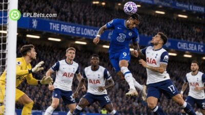 Chelsea striker João Pedro rises to head the ball against Tottenham defenders as the Spurs goalkeeper prepares to react during a Premier League match at Stamford Bridge.
