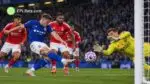 Ipswich Town attacker fires a shot towards goal as the Nottingham Forest goalkeeper dives to make a save, with Forest defenders looking on during a Premier League match illustration.