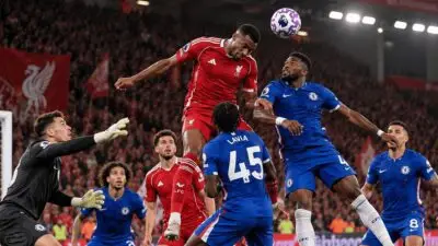 A Liverpool attacker rises to challenge for a header against Chelsea defenders as the goalkeeper attempts to reach the ball during a Carabao Cup clash at Anfield.