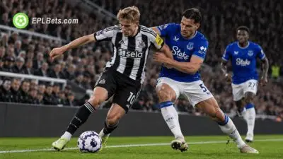 Jogador do Newcastle United protege a bola de um zagueiro do Everton durante uma disputa física perto da linha lateral no St James' Park.